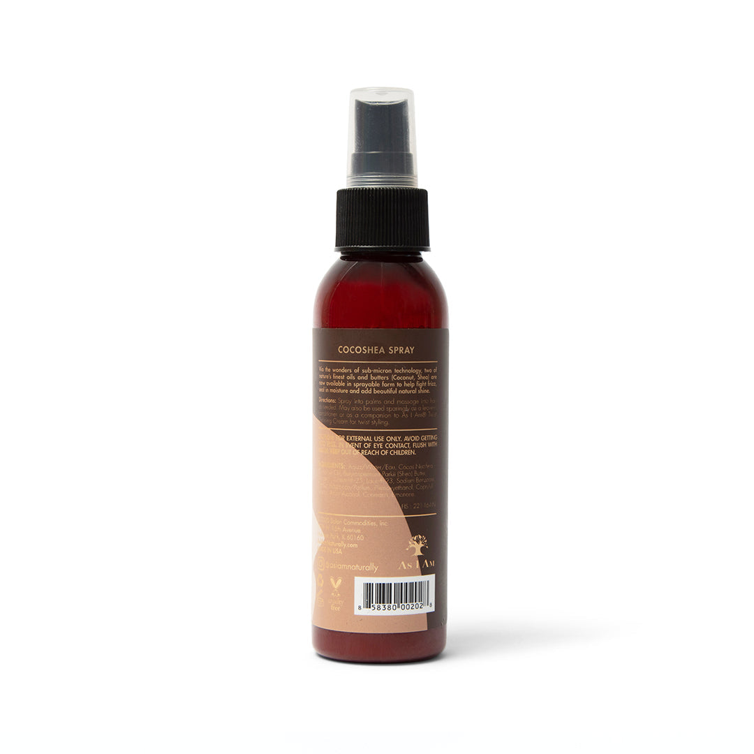 Bagside af en brun sprayflaske med en hvid etiket. Flasken indeholder As I Am Classic CocoShea Spray. Etiketten viser produktinformationer som ingredienser, anvendelsesvejledning og advarsler.