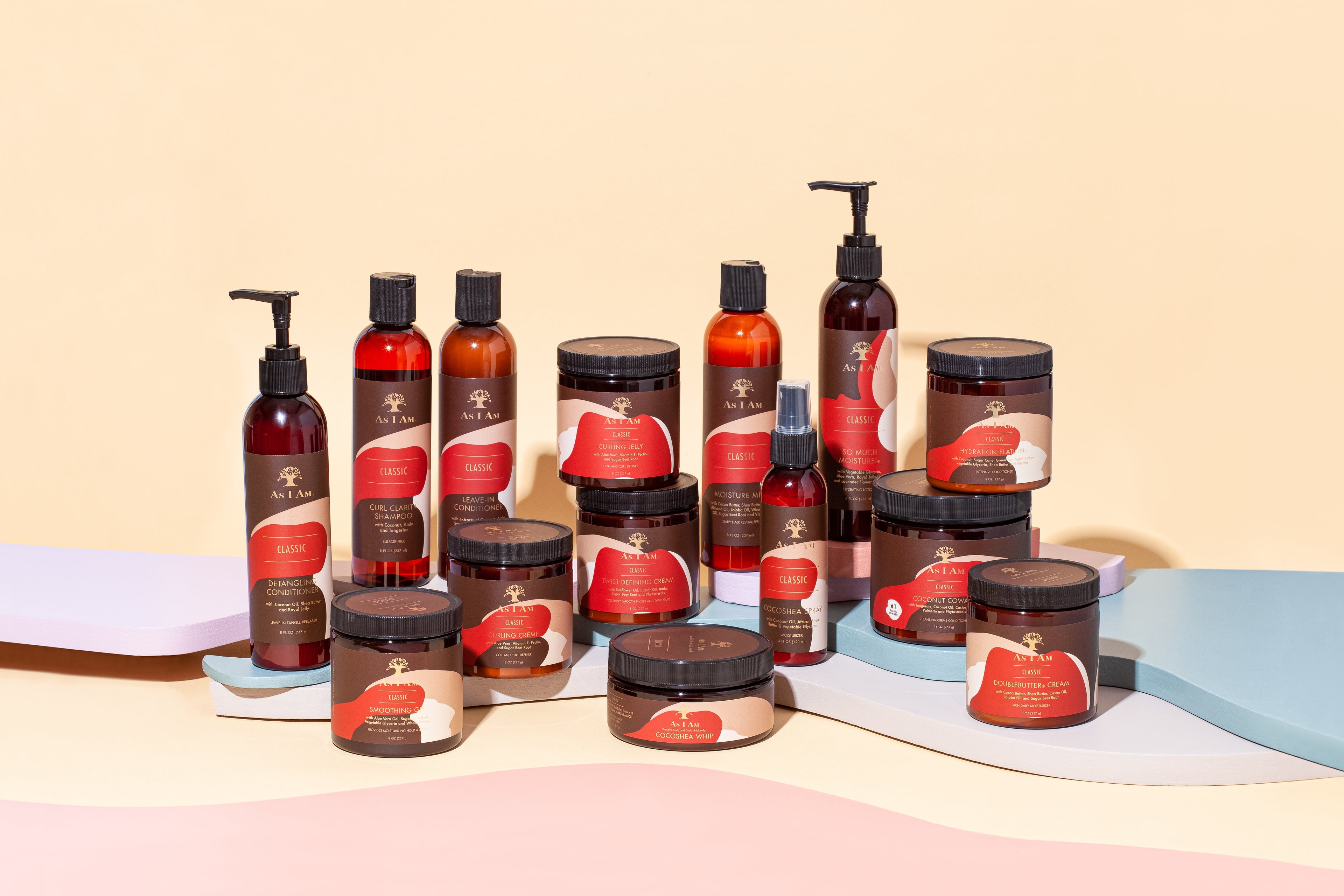 Et udvalg af As I Am hårplejeprodukter i brune glasbeholdere på en pastelfarvet baggrund. Produkterne inkluderer forskellige størrelser og typer, såsom cremer, olier og sprays. Alle produkter har en brun etiket med det karakteristiske As I Am-logo.