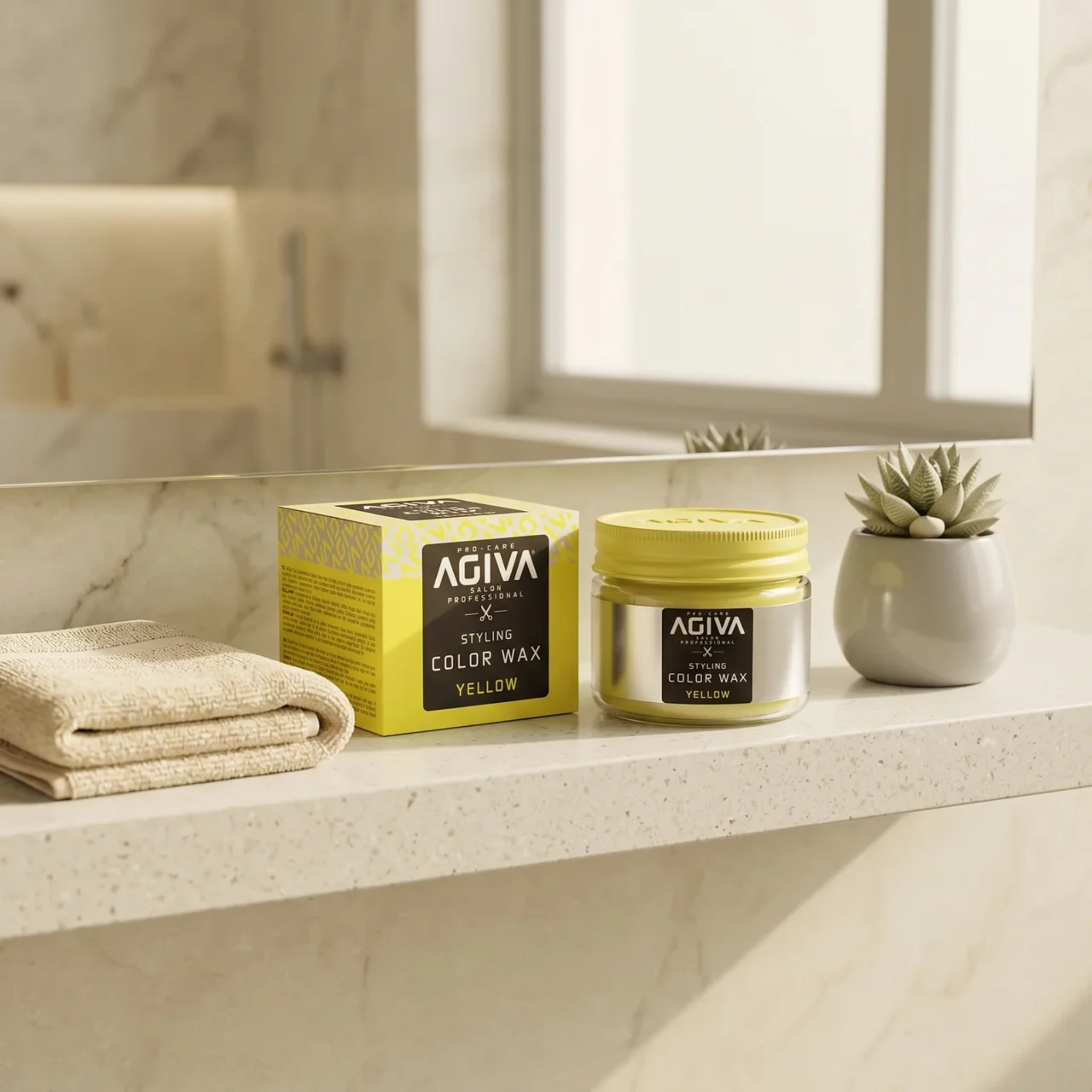 AGIVA Styling Color Wax Yellow i banke og æske på marmorbord med sukkulent og håndklæde i badeværelse.