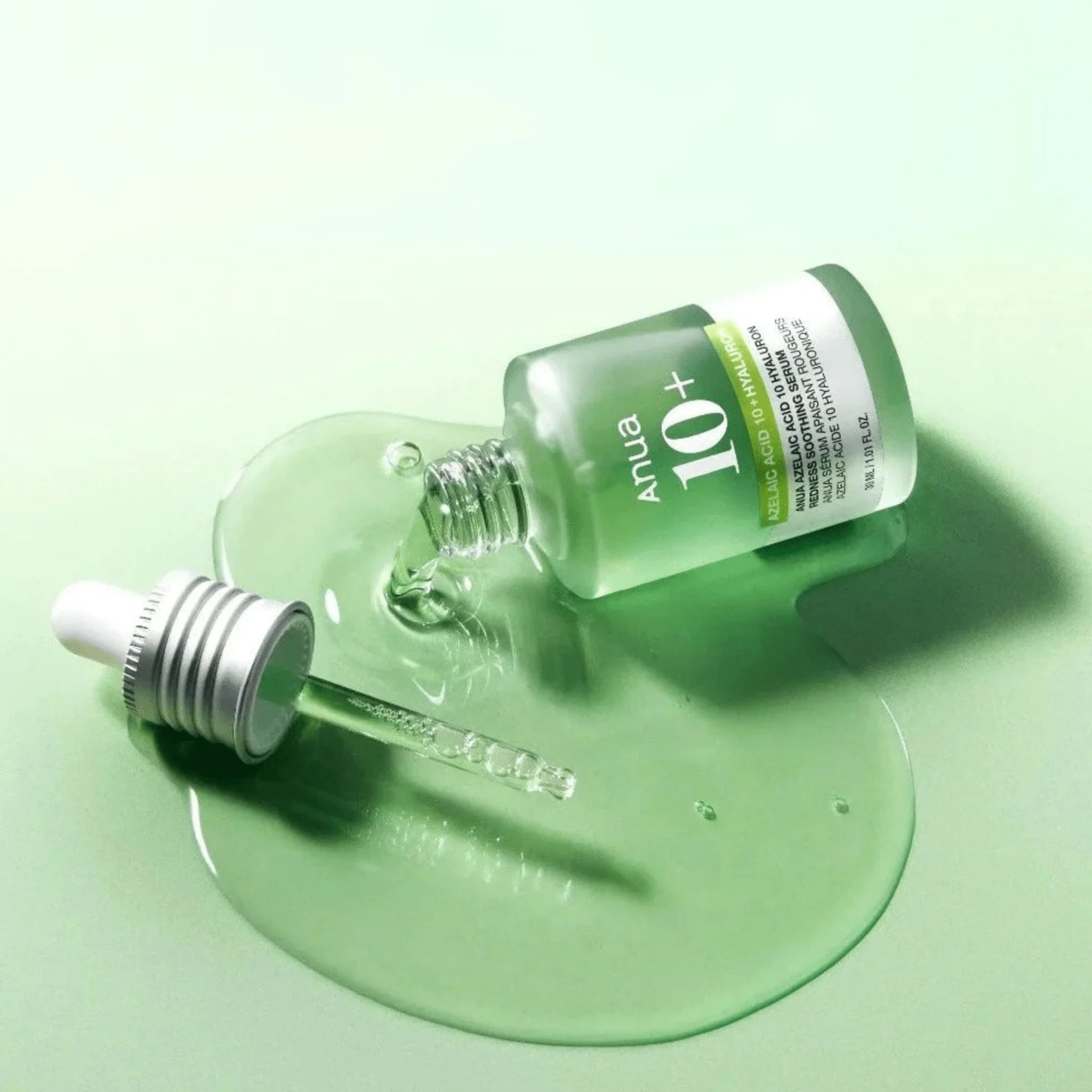 Anua 10+ Niacinamide serum med pipette liggende i spildt grønt serum på lysegrøn baggrund.