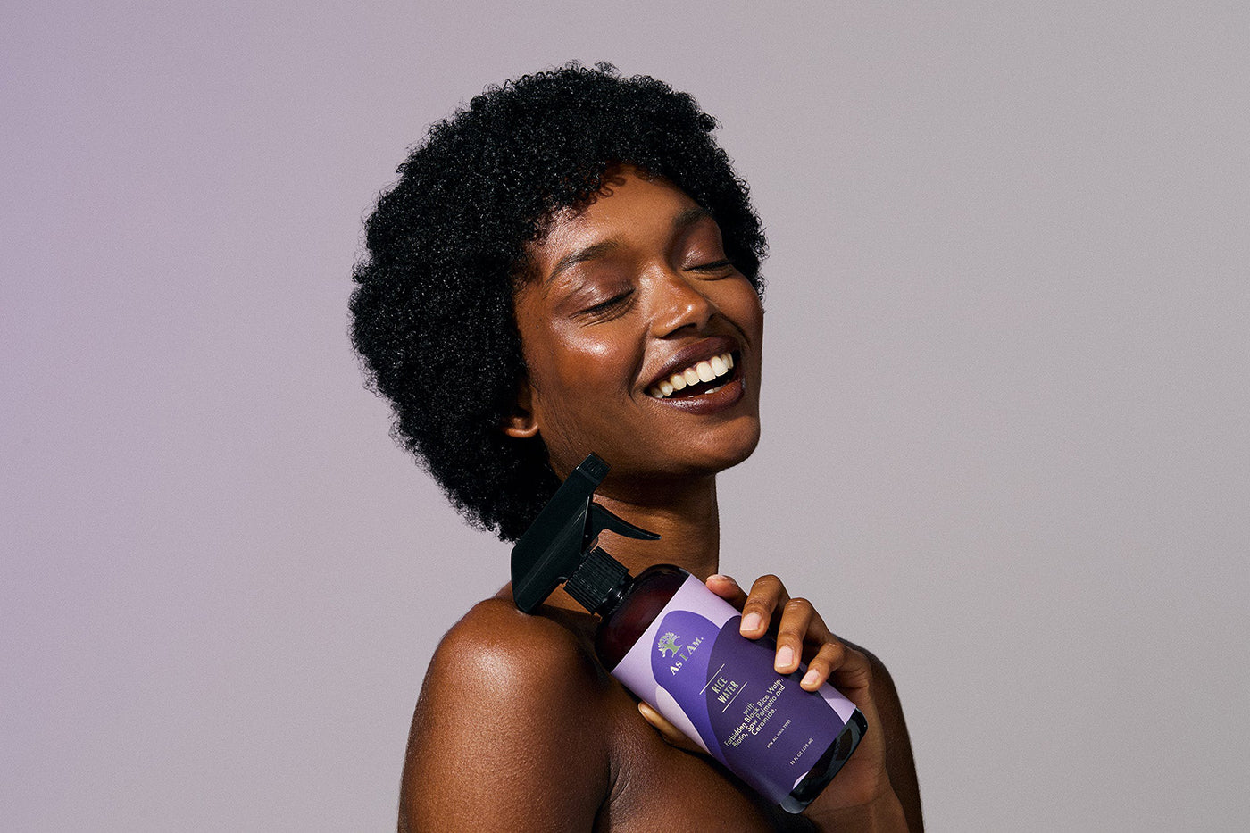 En kvinde holder en flaske As I Am Rice Water Spray.