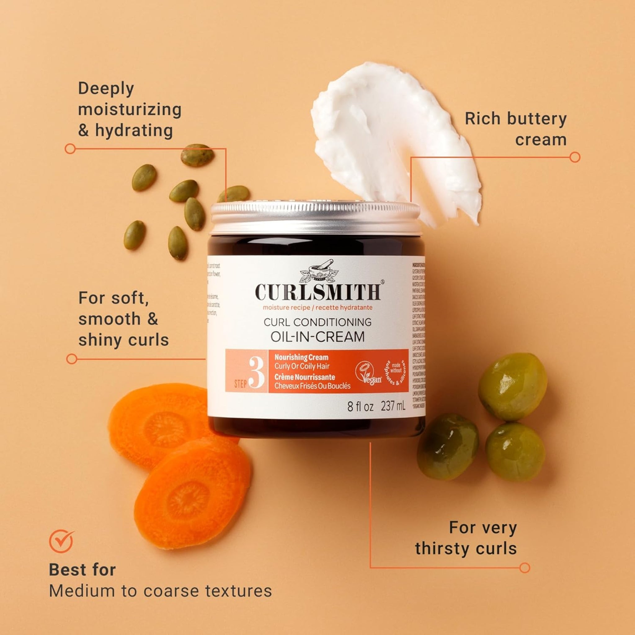 Curlsmith Curl Conditioning Oil-in-Cream i mørk glaskrukke med cremet tekstur, omgivet af gulerødder, oliven og græskarkerner.