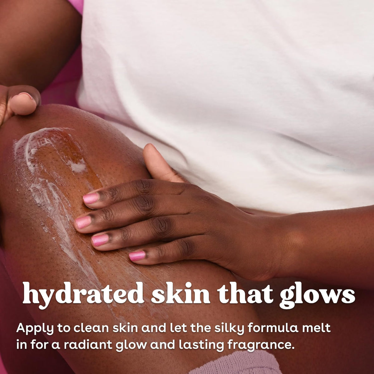 Hånd med lyserøde negle masserer creme ind i mørk hud på lår for hydreret skin that glows.