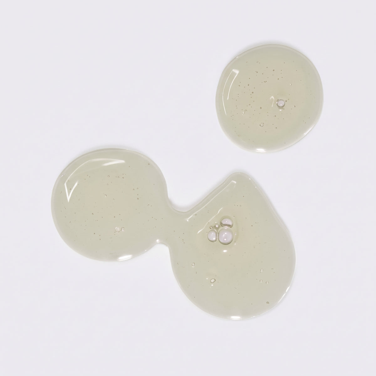 Gennemsigtig gel-serum i lysegrønne dråber med små bobler på hvid baggrund.
