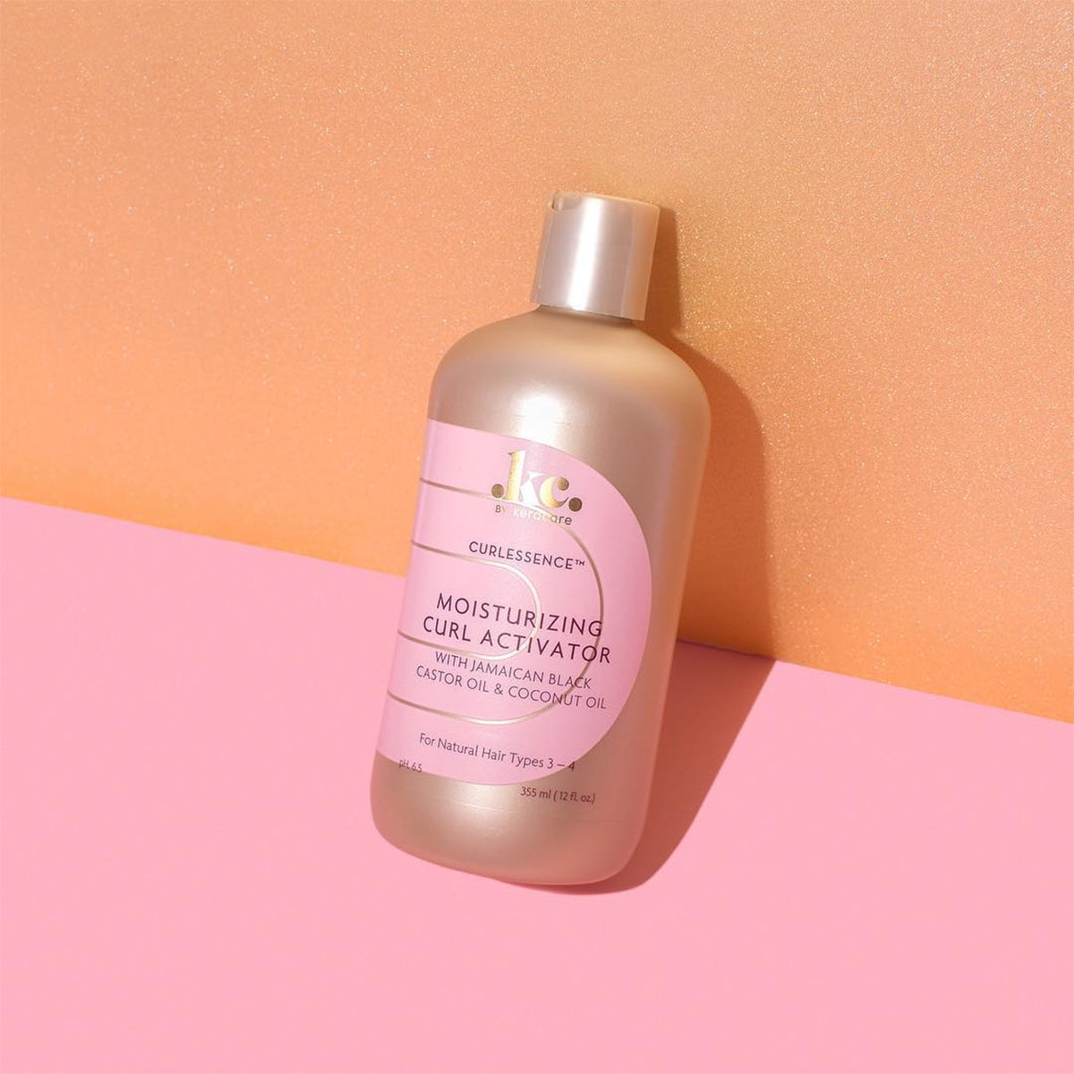 Keracare Curlessence Moisturizing Curl Activator til naturlige hårtyper 3-4, 355 ml flaske med guld låg, fotograferet mod en farverig baggrund.