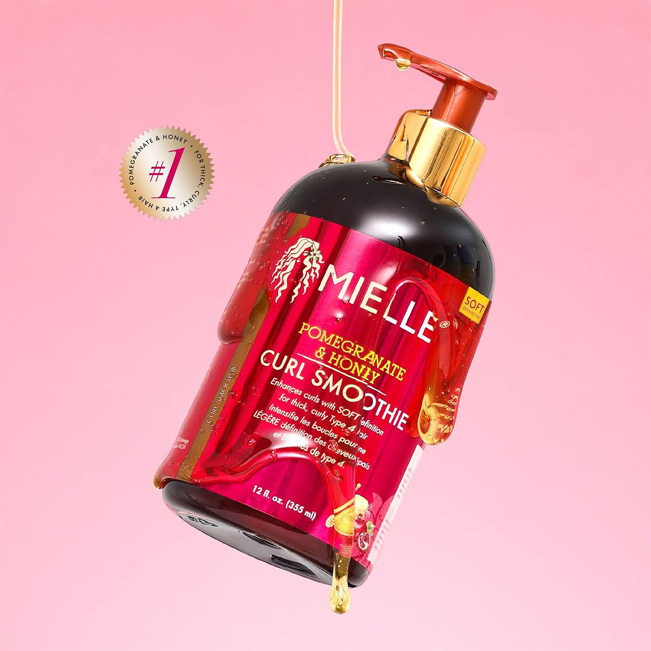 Mielle Pomegranate & Honey Curl Smoothie (355 ml) med guldpumpe og pink etiket på lyserød baggrund med dryppende produkt.