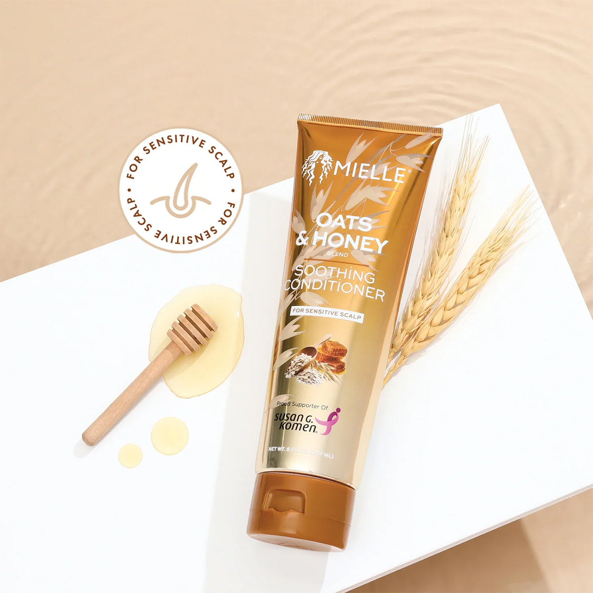 Mielle Oats & Honey Soothing Conditioner 237ml med honningske og havrestrå på hvid overflade ved vandoverflade.