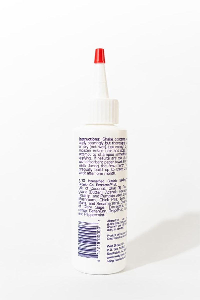 Never Before Now Growth Hair Oil 188ml set bagfra med hvid flaske og rød spids, tekstetiket med ingredienser og brugsanvisning.