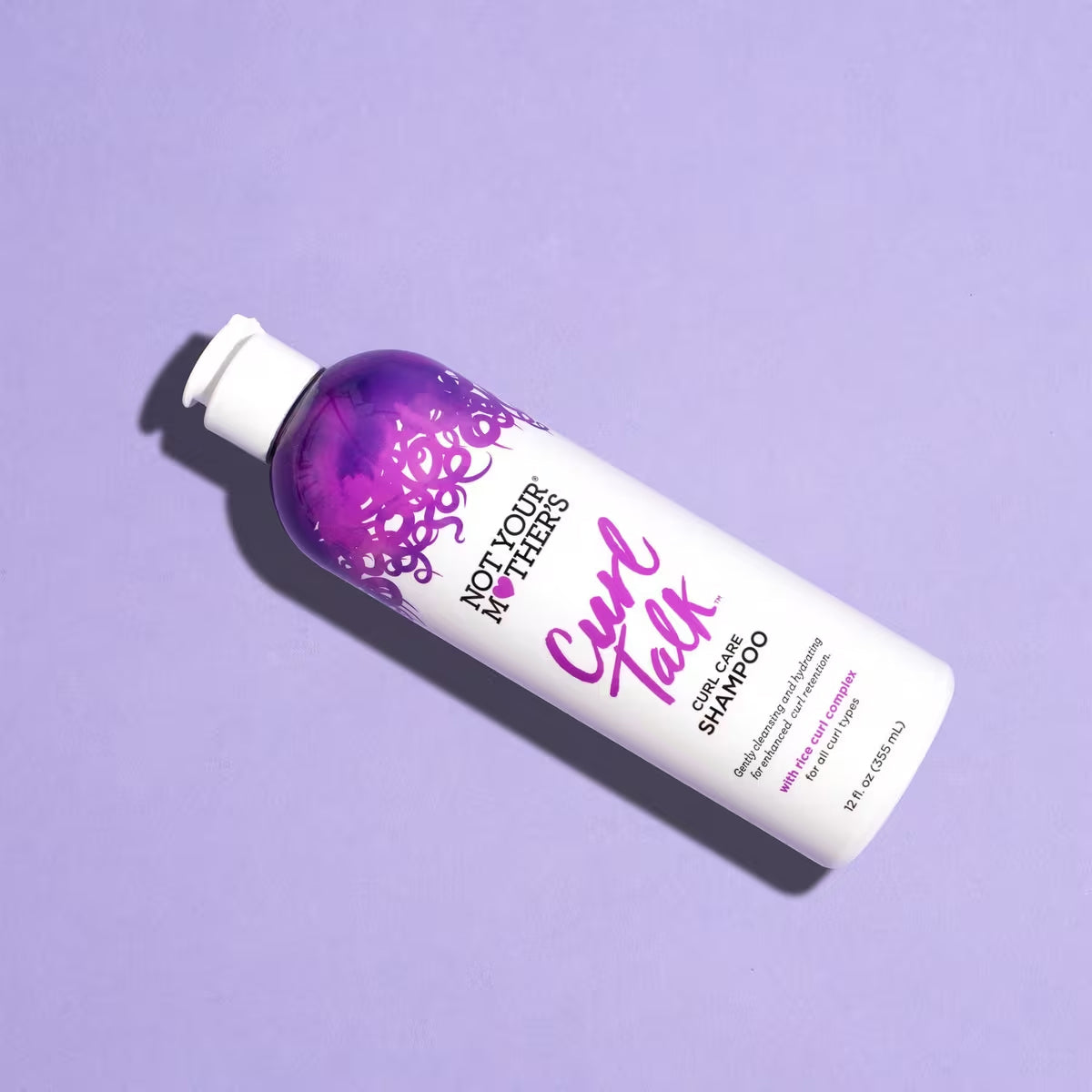 Produktbillede af Not Your Mother's Curl Talk shampoo til krøller, der ligger på en lilla baggrund, hvilket giver en alternativ præsentation.