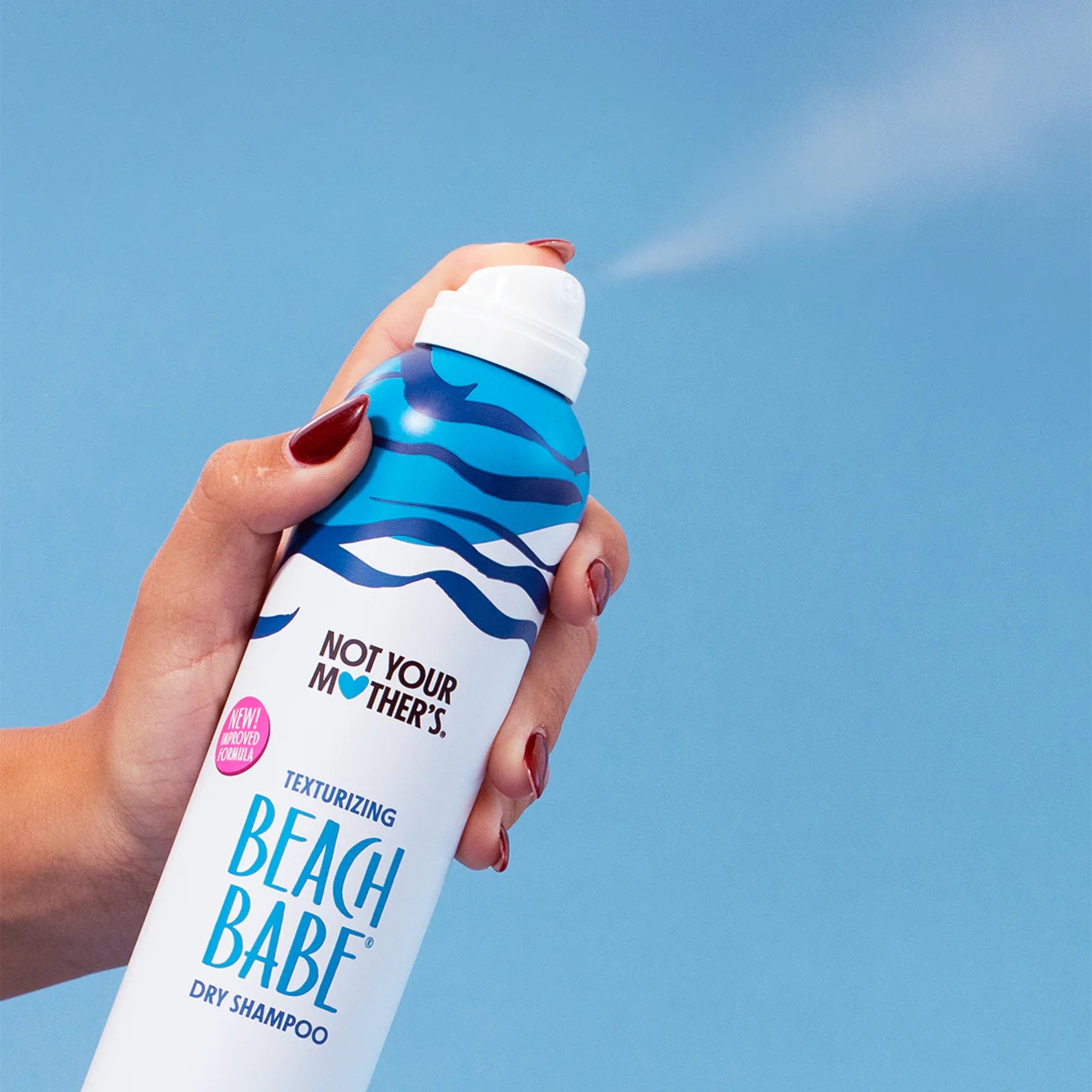 Hånd sprøjter Not Your Mother's Beach Babe texturizing dry shampoo mod blå himmel.