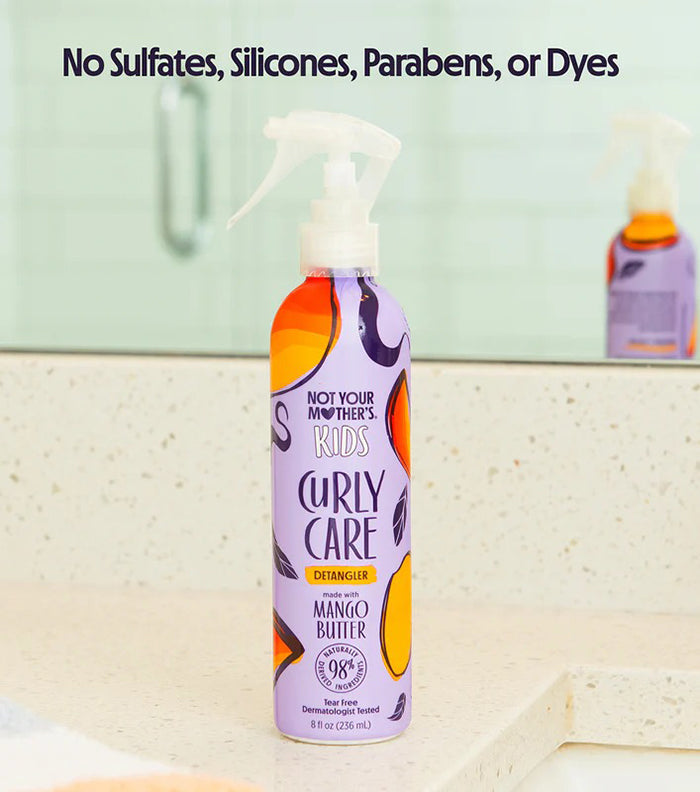 Not Your Mother's Kids Curly Care Detangler 236ml med mango-smør står på badeværelsesbord ved spejl.