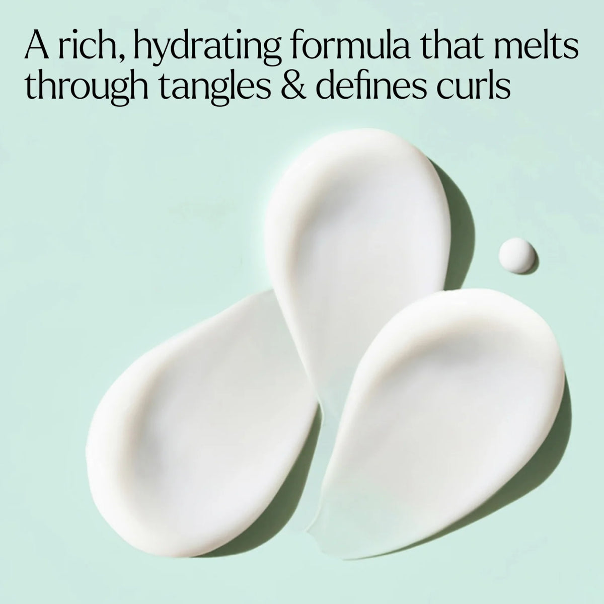 Cremet hvid hydrating hårformula i dråbeform på mintgrøn baggrund, definerer krøller og glatter ud tangles.