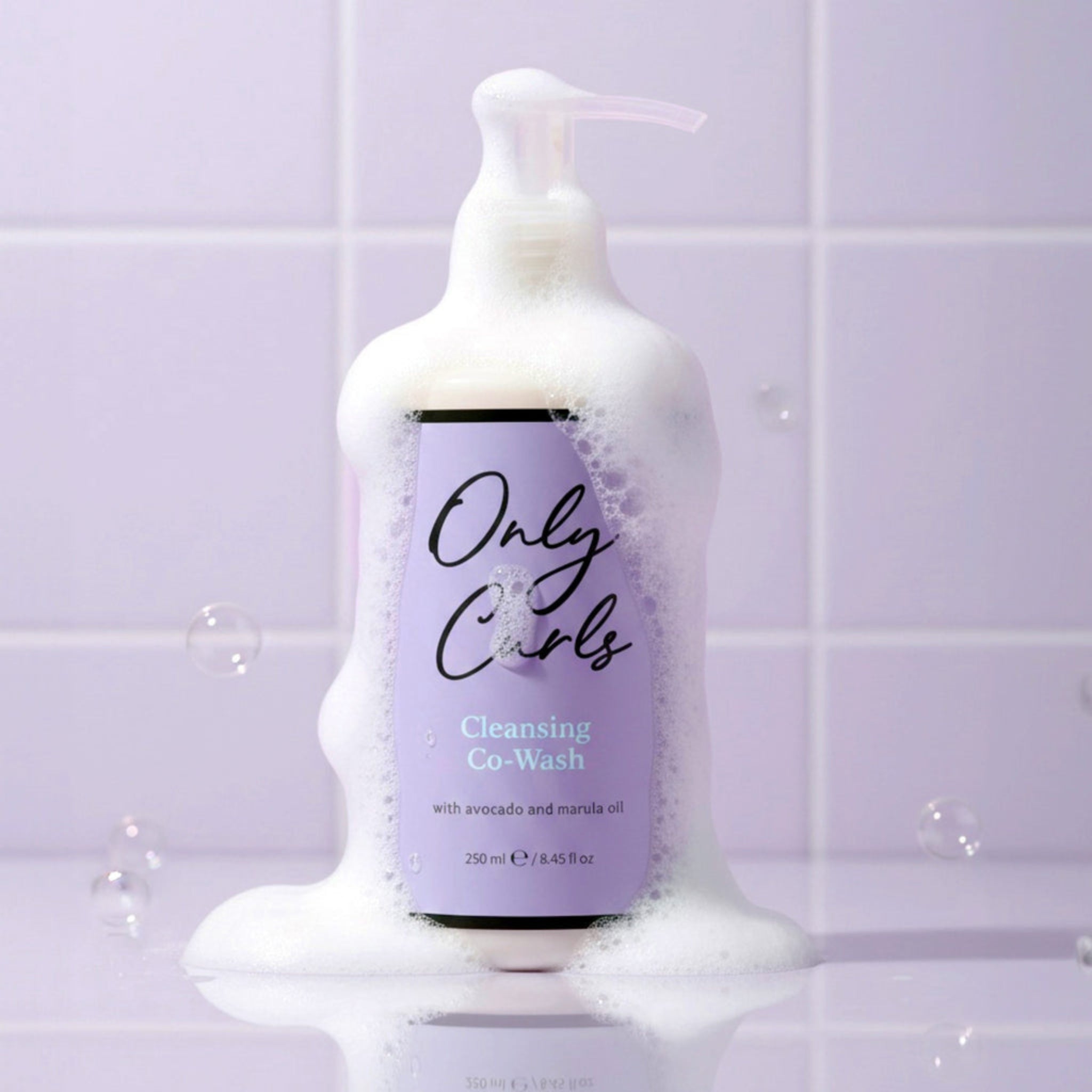 Only Curls Cleansing Co-Wash flaske med skum, 250 ml, mod lilla flisebaggrund.
