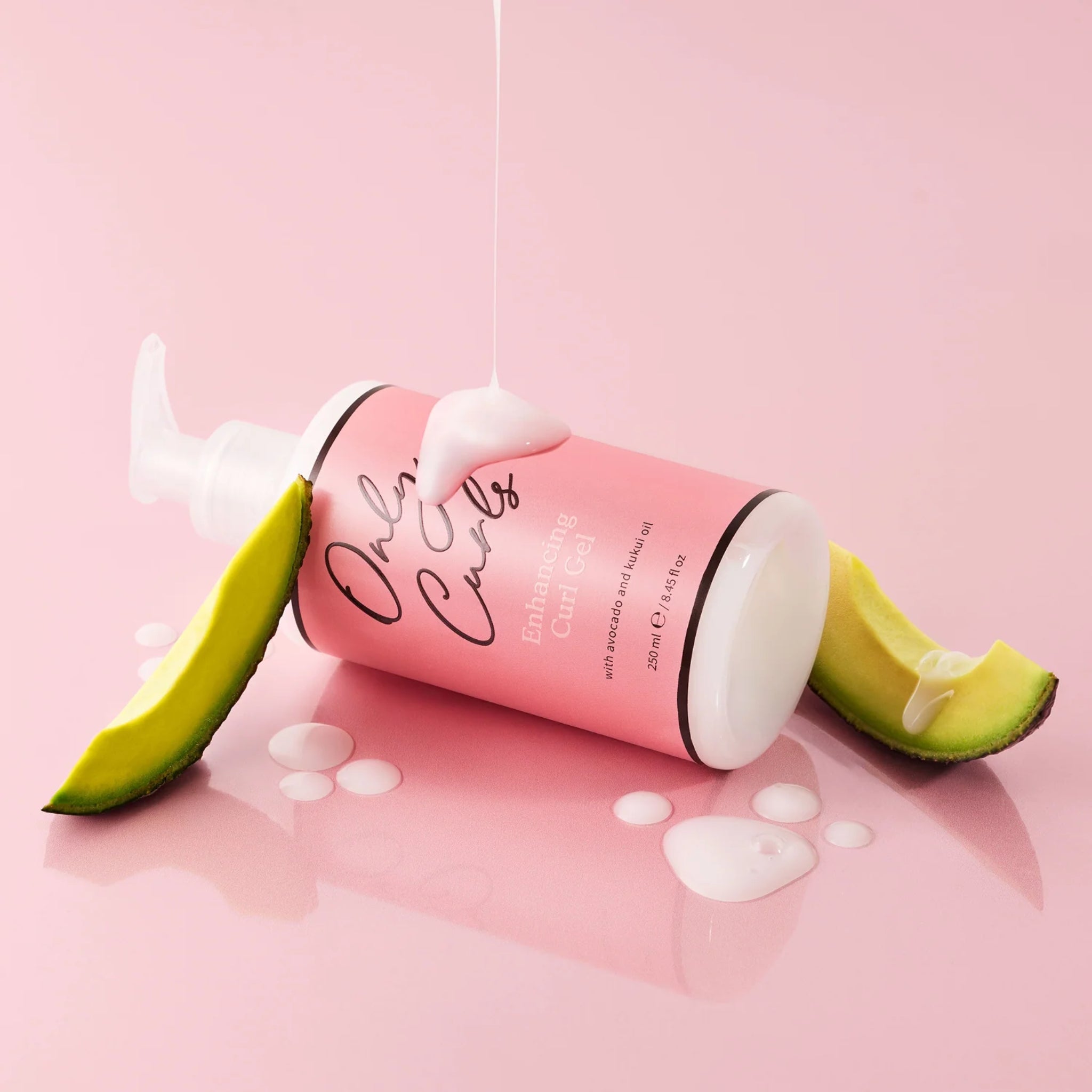 Only Curls Enhancing Curl Gel liggende på siden med avocadoskiver og gel, der drypper ned på lyserød baggrund.