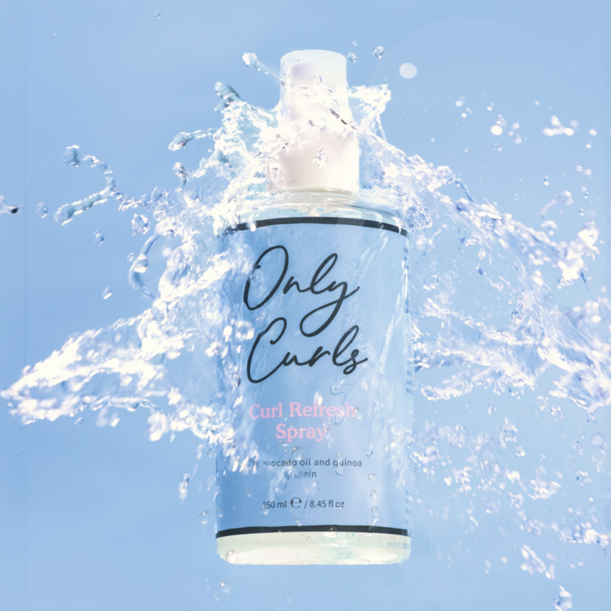 Only Curls Curl Refresh Spray-flaske, 250 ml, omsluttet af stænkende vand på lyseblå baggrund.