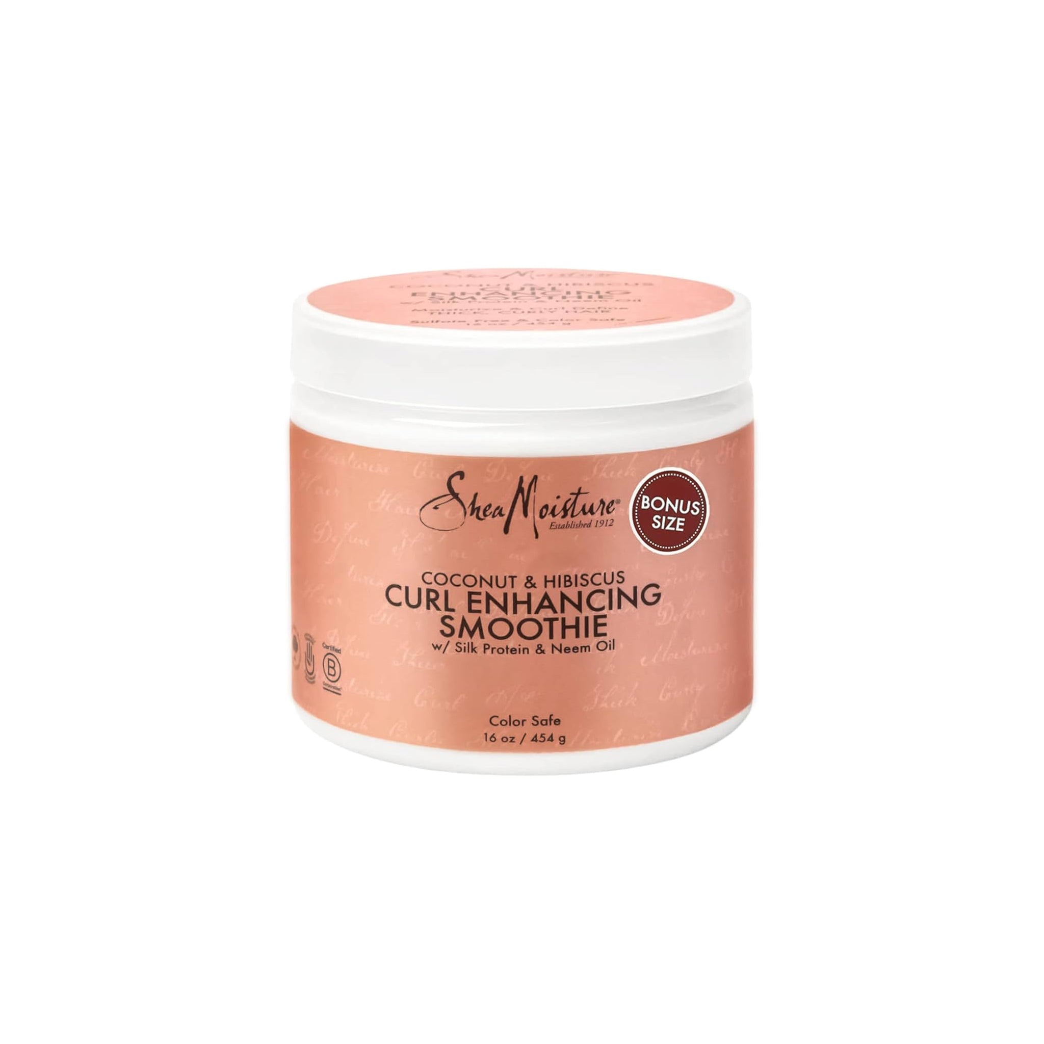 Shea Moisture Coconut & Hibiscus Curl Enhancing Smoothie (454 g). Etiketten er beige/lyserød med sort og rød tekst. En rød cirkel med teksten "BONUS SIZE" er også synlig.