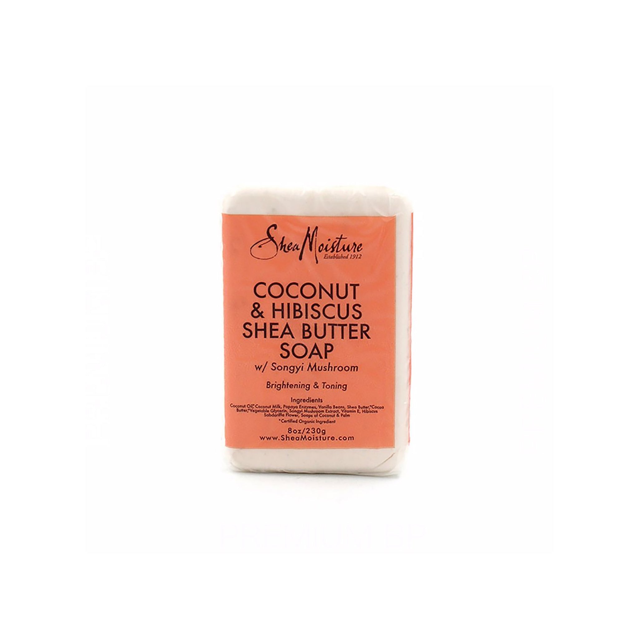 Hvid sæbebar indpakket i en beige/lyserød papiremballage med sort og rød tekst, der viser Shea Moisture Coconut & Hibiscus Shea Butter Soap (230 g).