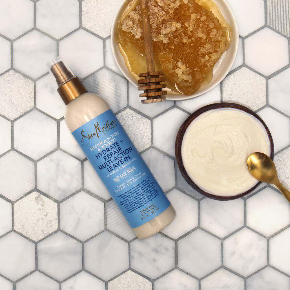 Shea Moisture Manuka Honey & Yogurt Hydrate + Repair Multi-Action Leave-In (237 ml). Fugtgivende leave-in balsam med manukahonnig og yoghurt, illustreret med honningkage og yoghurt.